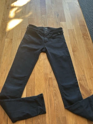 Svarta Replay jeans med smal passform - Säljer ett par svarta jeans från Replay med smal passform och klassisk femficksdesign. Jeansen har snygga detaljer vid fickorna och är tillverkade i ett mjukt bomullsmaterial med stretch för extra komfort. Perfekta för en stilren och modern look.