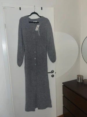 Lång grå stickad kofta med knappar - Säljer denna fina, stickade långklänning. Prislappen är kvar på. 🩷