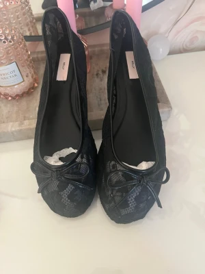 Svarta spetsballerinaskor från Nelly - Säljes då jag köpte fel storlek! Aldrig använda. Säljer ett par svarta ballerinaskor från Nelly med elegant spetsdetalj och liten rosett framtill. Skorna har rundad tå och låg sula.