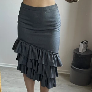 Grå kjol med volanger - Säljer en snygg grå kjol med flera lager volanger nedtill. Kjolen har en figurnära passform upptill och är tillverkad i ett mjukt material. Hör av er vid frågor om mått osv💗