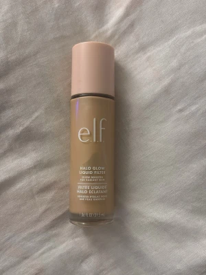 e.l.f. Halo Glow Liquid Filter foundation - e.l.f. Halo Glow Liquid Filter är en flytande foundation i glasflaska med ljusbeige ton och glow-effekt. Kommer med en stilren ljusrosa kork och ger huden en strålande finish. Perfekt för dig som vill ha en naturlig lyster och enkel applicering. Köptes för 199 kr säljs för 129 för den är använd , färg 2