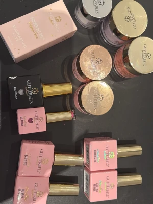 Glitterbels nagellack och gelékit - Säljer ett kit med flera nagellack och geléer från Glitterbels. Färgerna varierar mellan rosa, svart, lila och orange. Flaskorna har guldfärgade lock och klassisk rektangulär form. Innehåller både gel polish, basecoat, primer och builder gel. Perfekt för dig som vill skapa snygga naglar hemma.