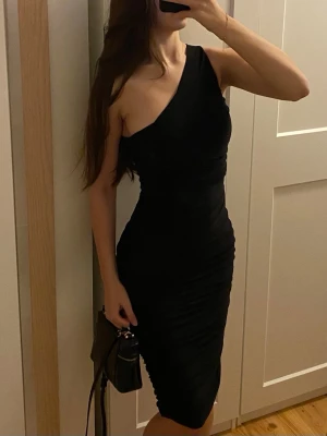 Svart klänning - Svart one shoulder klänning. Använd 1 gång.