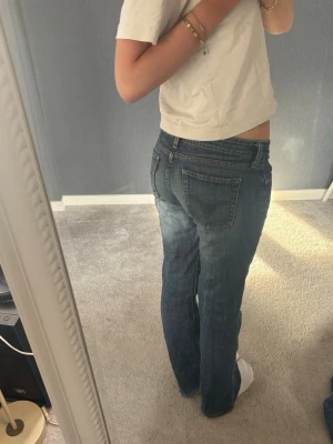 Blå raka jeans från Levi's - Säljer ett par klassiska blå jeans från Levi's med rak passform och låg midja. Jeansen har fem fickor, knappgylf och subtila slitningar för en avslappnad look. Perfekta till vardags och passar till det mesta. Materialet är denim i bomull.