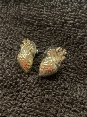 Örhängen i form av anatomiska hjärtan IOAKU - Unika örhängen i silverfärgad metall formade som anatomiska hjärtan med detaljerade ådror och vener. Perfekt accessoar för dig som gillar coola och annorlunda smycken. Säljs som ett par.