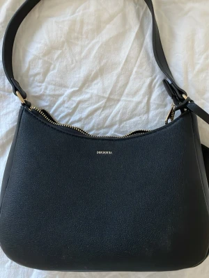 Svart axelväska från Don Donna - Svart axelväska från Don Donna med guldfärgade detaljer och dragkedja upptill. Jätte vacker 💕