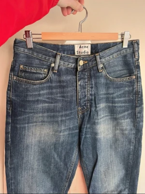  Acne Studios - Säljer ett par snygga blå jeans från Acne Studios med klassisk femficksmodell och raka ben. Jeansen har en tvättad look med slitningar och ljusare partier framtill. Tillverkade i denim med en cool vintagekänsla. Perfekta för en avslappnad stil.