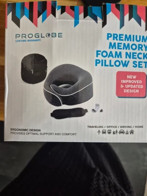PROGLOBE minnesskum nackkudde - Resekudde i svart minnesskum från PROGLOBE med ergonomisk design och justerbar kardborre. Kudden har vit kant och levereras med förvaringspåse, sovglasögon  och öronproppar. Perfekt för långa resor eller när du vill vila bekvämt sittande.