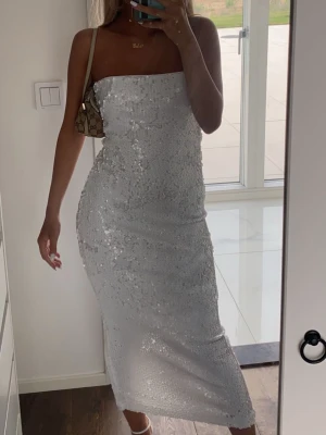 Vit paljettklänning  - Säljer en snygg vit klänning med paljetter. Klänningen har en rak, figurnära passform och är i midilängd. Perfekt för dig som vill sticka ut med en glittrig look. Passar till alla som älskar att glänsa.