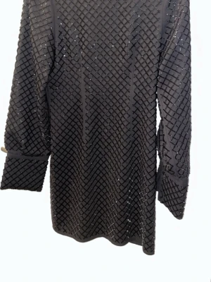 Svart glittrig långärmad topp - Snygg svart topp med glittrigt rutmönster och långa ärmar. Perfekt för dig som vill sticka ut lite extra. Materialet känns mjukt och stretchigt, och toppen har en rak passform. Passar till både jeans och kjol.