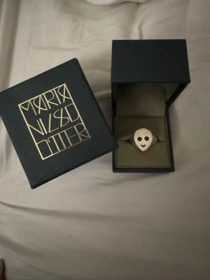 Silverring från Maria Nilsdotter - Cool silverring från Maria Nilsdotter med ett unikt ansiktsmotiv. Ringen har en matt finish och är tillverkad i silver. Kommer i original ask med logga. Perfekt statement-piece för dig som gillar unika smycken. Som säljs inte längre ❤️