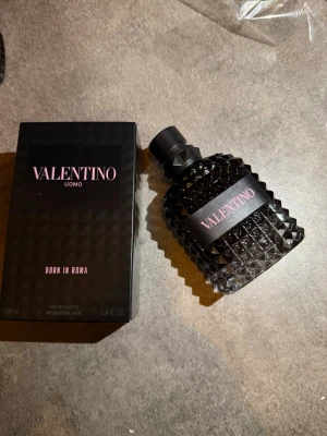 Valentino Uomo Born In Roma EdT 100ml - Valentino Uomo Born In Roma är en exklusiv herrparfym i en svart, nitat glasflaska med rosa detaljer. Flaskan har en unik, lyxig design och kommer i en matchande svart kartong med rosa text. Innehåller 100 ml Eau de Toilette. Kvitto finns