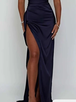 Marinblå långklänning med slits - Snygg marinblå långklänning i glansigt material med hög slits och oneshoulder-design. Klänningen har en figurnära passform och draperad detalj vid midjan som ger en elegant siluett. Perfekt för dig som vill sticka ut på bal eller fest.