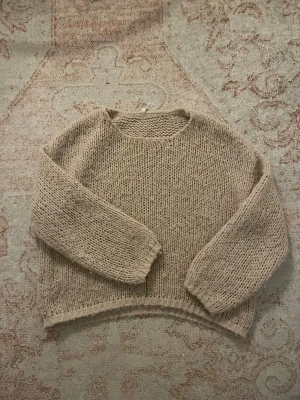 Beige stickad tröja från ONLY - Mysig beige stickad tröja från ONLY med grovstickad struktur och rund hals. Tröjan har lång ärm och en relaxed passform som passar perfekt till jeans eller kjol. Enkel och stilren design som är lätt att matcha.