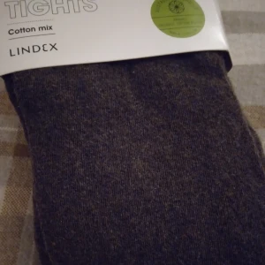 HELT NYA OANVÄNDA bruna tights / strumpbyxor från Lindex, S 36/38 - Tjocka och mjuka bruna/mörkbruna tights/strumpbyxor från Lindex i storlek S 36/38, men Passar troligen även någon med XS-S. Tillverkade i en skön bomullsblandning med ekologisk bomull, polyamid och elastan. Perfekta att bära under kjol eller klänning när du vill ha extra värme och komfort. Passar extra fint på hösten. Felfria.