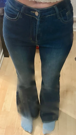 Mörkblå bootcut jeans med hög midja - Säljer ett par mörkblå bootcut jeans med hög midja. Jeansen har utsvängda ben. Perfekta för dig som gillar en retroinspirerad look och vill ha ett par jeans som sticker ut lite extra.