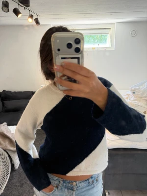Stickad tröja med blåvit diagonal - Säljer en stickad tröja med coolt diagonalt mönster i blått och vitt. Tröjan har lång ärm, rund halsringning och är lite croppad i modellen. Perfekt till jeans för en avslappnad look.