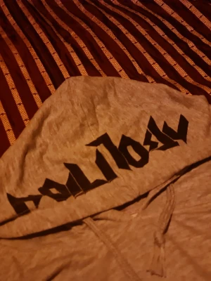 Grå hoodie med svart tryck - Snygg grå hoodie med svart grafiskt tryck på både huvan och längs båda ärmarna. Hoodien har dragsko i huvan och ribbade muddar vid ärmslut och nederkant. Perfekt för en avslappnad streetstyle-look.