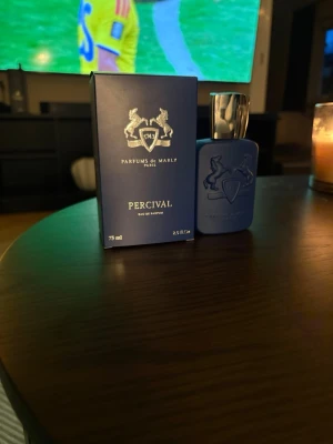 Parfums de Marly Percival EdP 75ml - Parfums de Marly Percival Eau de Parfum i en snygg mattblå flaska med silverfärgad kork. Flaskan har en elegant relief med två hästar och sköld, och kommer i matchande blå kartong. En exklusiv och modern doft för dig som gillar lyxiga parfymer. Så gott som ny använd några fåtal sprut