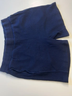 Mörkblå ribbade stickade shorts - Mörkblå shorts i ribbad stickad design. De har en elastisk midja och är gjorda i ett mjukt, stretchigt material som ger en bekväm passform. Perfekta för avslappnade dagar eller som mysplagg hemma.
