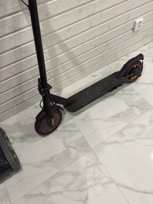 Svart elscooter med röda detaljer - Säljer en svart elscooter med röda detaljer på hjulen och reflexer. Scootern har en bred ståplatta och robust ram i metall. Perfekt för att ta sig fram snabbt i stan eller till skolan.