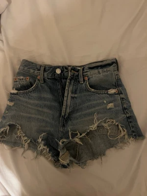 Snygga  jeansshorts med slitningar.  - Snygga  jeansshorts i blå denim med råa, fransiga kanter och slitningar både fram och bak. Klassisk femficksmodell med knapp och dragkedja. Perfekta för en avslappnad och trendig look.🥰