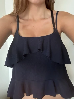 Mörkblå volang topp med smala band - Snygg somrig mörkblå volang topp! Köpt på Nelly för 259kr storlek S, kommer inte till användning längre, använd 1 gång typ. Skit snygg och prtkfekt till en extra tuch på en outfit, sommaren, fest, festival mm 