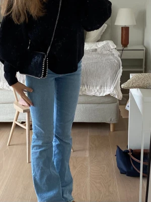 Ljusblå bootcut jeans - Säljer ett par ljusblå bootcut jeans med klassisk femficksmodell och hög midja. Jeansen har en snygg, något utsvängd passform nedtill och är perfekta för en avslappnad men trendig look. Tillverkade i ett mjukt denimtyg som är bekvämt att bära hela dagen.