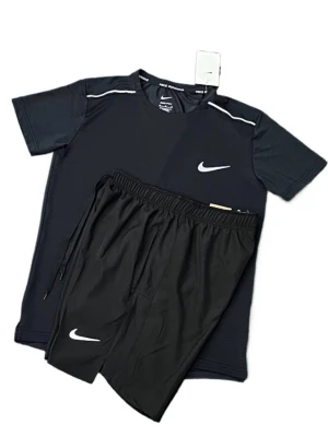 Nike miler Set - Snyggt svart träningsset från Nike med t-shirt och shorts. T-shirten har vita detaljer vid axlarna och Nike-logga på bröstet. Shortsen har resår i midjan och vit Nike-logga på benet. Perfekt för gymmet eller löprundan.