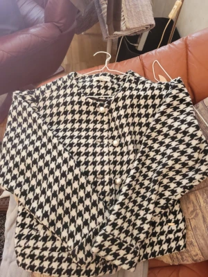 Rutig cardiganjacka från Holly & Whyte - Snygg cardiganjacka från Holly & Whyte by Lindex i svartvitt rutigt mönster. Jackan har pärlknappar framtill och är tillverkad i ett mjukt material som känns lyxigt. Perfekt för dig som vill ha en trendig och klassisk look.
