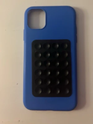 Blått mobilskal med en sugpropp (Iphone11) - Snyggt blått mobilskal med svart sugpropp på baksidan. Man kan använda sugproppen till att sätta fast den på antingen fönstret eller spegeln. Tillverkat i mjukt silikonmaterial som ger bra grepp och skydd till din mobil. Priset kan diskuteras.