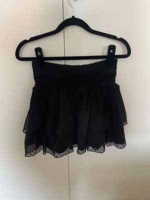 Svart volangkjol - Svart volangkjol med små prickar från Gina Tricot. Har sytt midjebandet lite kortare då den gick väldigt högt upp så ser tyvärr inte vilken storlek det är men är XS/S. 