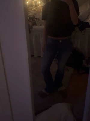 Blå bootcut jeans med låg midja - Säljer ett par klassiska blå bootcut jeans med låg midja från HMs barnavdelning. Jeansen har en enkel design och sitter snyggt över höfterna.  På näst sista bilden ser man en slitning som är en del av jeansens modell. Helt oanvända!! 
