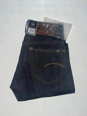 G-star jeans - Snygga mörkblå jeans från G-Star RAW, modell 3301 Tapered. Jeansen har en smalare passform med avsmalnande ben och är tillverkade i slitstarkt denimtyg. Midja 34cm, längd 100cm. JAG SKICKAR EJ FLER BILDER NÄR JAG BÄR JEANSEN! för storleksguide hänvisar jag till måtten och för bättre inblick i passformen rekommenderar jag att googla på modellnamnet. kolla måtten noggrant :) 74