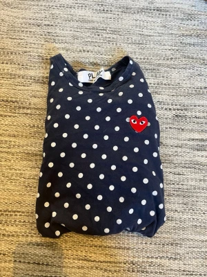 Mörkblå prickig CDG tröja  - Mörkblå långärmad tröja från Comme des Garçons PLAY med vita prickar och det ikoniska röda hjärtat broderat på bröstet. Tillverkad i mjuk bomull och har en klassisk rund halsringning. Tröjan är i storlek l men passar storlek S/xs . Hör av dig vid minsta fundering av plagget!😀