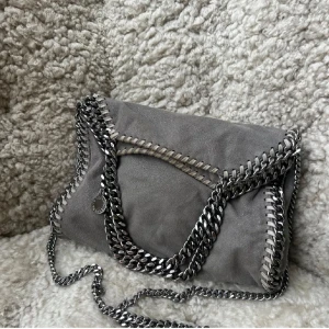 Stella McCartney väska  - Intressekoll på denna sjukt snygga, rymliga och stilrena Stella McCartney väska. Den är grå och i modellen Falabella mellan storleken! Köptes för några månader sedan. Ett hål i innerfodret i innerfickan och lite lite rost men annars inga defekter och man ser det absolut inte vid användning, jag har inte heller störts av det alls! Kom gärna med bud💞💞