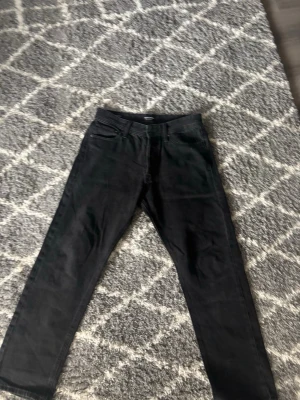 Svarta raka jeans Jack & Jones - Säljer ett par svarta jeans med rak passform och klassisk femficksdesign. Jeansen har bälteshällor och knappgylf. Perfekta till en avslappnad stil och funkar året runt. Materialet känns som bomull med lite stretch.