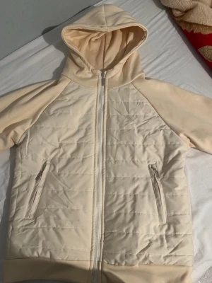 Beige quiltad hoodie med dragkedja - tja,  Snygg beige hoodie( jacka)  den är HELT NY!!  inte använd en enda Gång!! Och ja råkade köpa fel storlek till mig själv  (S) och kommer ej till användning.