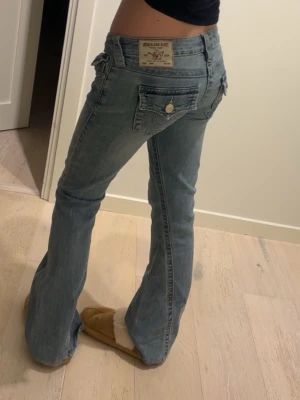 Ljusblå bootcut jeans från True religion - Ljusblåa bootcut true religion jeans med vit spets i fickan 🥹❣️De är uppsydda! Passar mig som är ca 160 💕