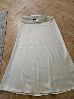 Vit långkjol i satin - Snygg kjol i satin. Cream färgad, storlek 34. Nyskick utan prislapp.