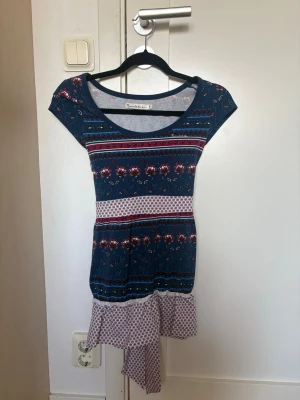 Blommig blå kortklänning med knyt - Supersöt kortklänning i blått med blommigt mönster.