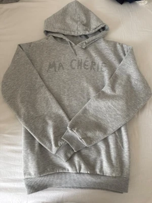 Grå hoodie med text MA CHÉRIE - Snygg grå hoodie med huva och texten 'MA CHÉRIE' broderad framtill. Storlek 158-164!!🩶
