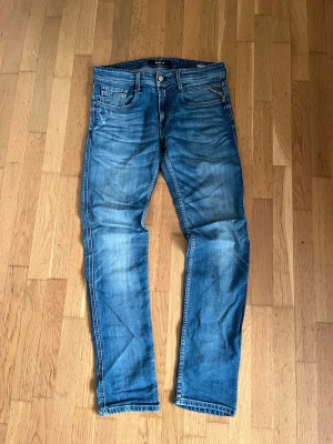 Vintage archive replay jeans  - Snygga blå slim fit/raks jeans från Replay med klassisk femficksdesign och diskreta slitningar framtill och ett hål på ena benet som hör till designen! Jeansen har normal midja och raka ben, tillverkade i denim med lätt stretch för extra komfort. Perfekta för en avslappnad och vintage look och dessa har sjukt snygg tvätt! Priset är ej hugget i sten!