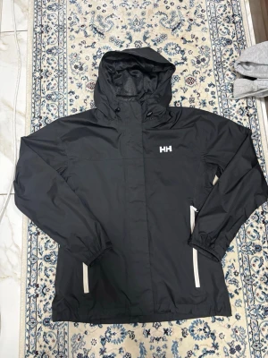 Helly hansen vindjacka - Svart Helly Hansen jacka. Använd 1 gång, nyskick. Lätt och perfekt som vind/regnjacka. Passar S-M 