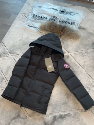 Snygg grå vinterjacka med röd logga - En stilren och väldigt varm vinterjacka. Perfekt för kalla vinterdagar – man fryser verkligen inte i den. Stabil kvalitet, snygg design och väldigt skön att ha på sig. Samt äkta räv päls. Helt oanvänd