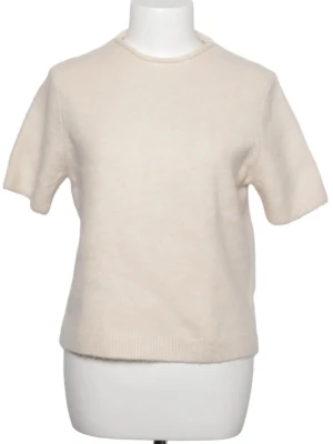 Beige stickad topp med kort ärm - En stilren beige stickad topp med korta ärmar och rund hals. Perfekt att matcha med jeans eller kjol för en enkel och snygg look. Mjuk och skön känsla tack vare det stickade materialet.