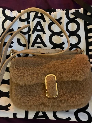 Brun fluffig handväska Marc Jacobs - Superfin brun handväska från Marc Jacobs i mjukt teddy-material med guldfärgat spänne. Helt ny aldrig använd. Nypris 4300kr mitt pris 1999kr💕