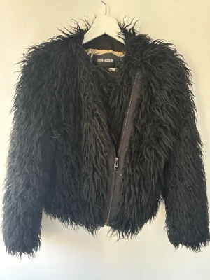Zadig & Voltaire pälsjacka  - Säljer en svart, fluffig pälsjacka från Zadig & Voltaire med lång päls och sned dragkedja framtill. Pälsjackan har en cool döskalles design  på insidan. Jackan är köpt i london flera år tillbaka men nästan aldrig används. 
