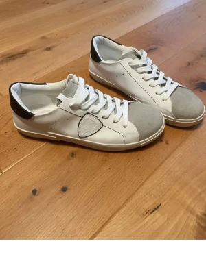 Vita Philippe Model sneakers med grå tå - Snygga vita sneakers från Philippe Model med grå mockadetalj på tån och svart häl. Klassisk låg modell med vita snören och logga på sidan. Perfekta för en clean och stilren look. HELT NYA!!!!