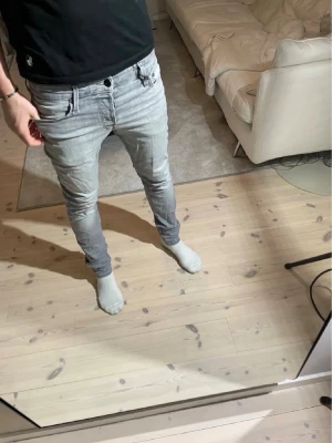 Ljusgrå Jack & Jones  - Säljer ett par ljusgrå slim fit jeans från Jack & Jones med klassisk femficksdesign och dragkedjegylf. W30 L32. Jeansen har en modern, smal passform och är tillverkade i stretchigt denimtyg för extra komfort. Perfekta för dig som gillar en stilren och enkel look.